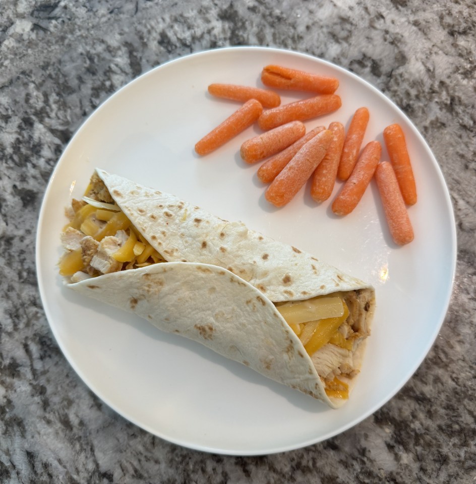 Chicken wrap with cheese and baby carrots on a plate.