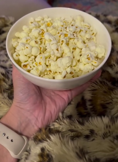 A hand holding a bowl of popcorn.