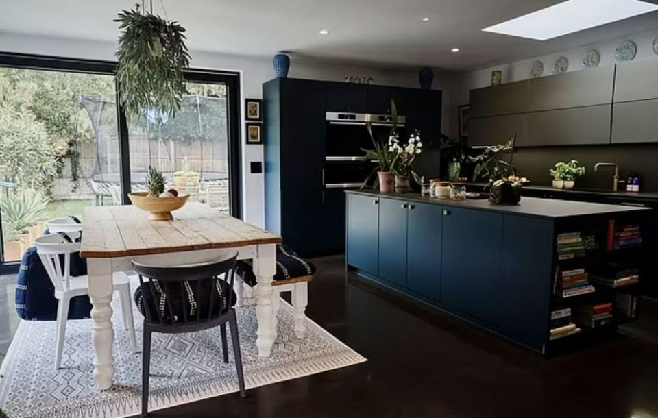 Modern kitchen and dining area with dark blue cabinetry and a farmhouse-style table.