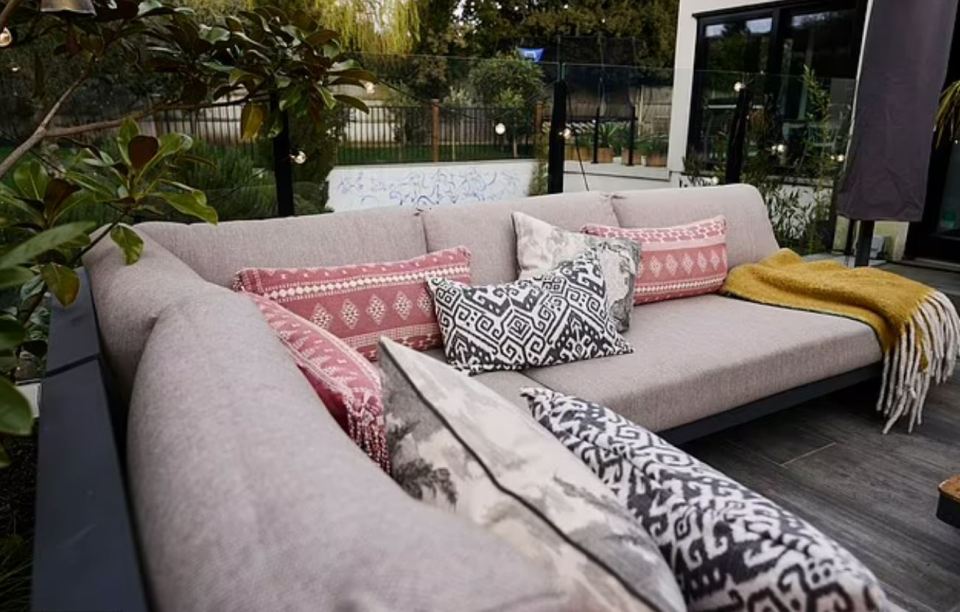 Outdoor sectional sofa with patterned pillows and a throw blanket.