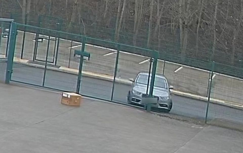 CCTV image of a delivery driver throwing a package over a fence.