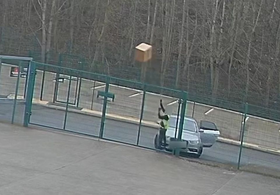 CCTV footage of a delivery driver throwing a parcel over a fence.