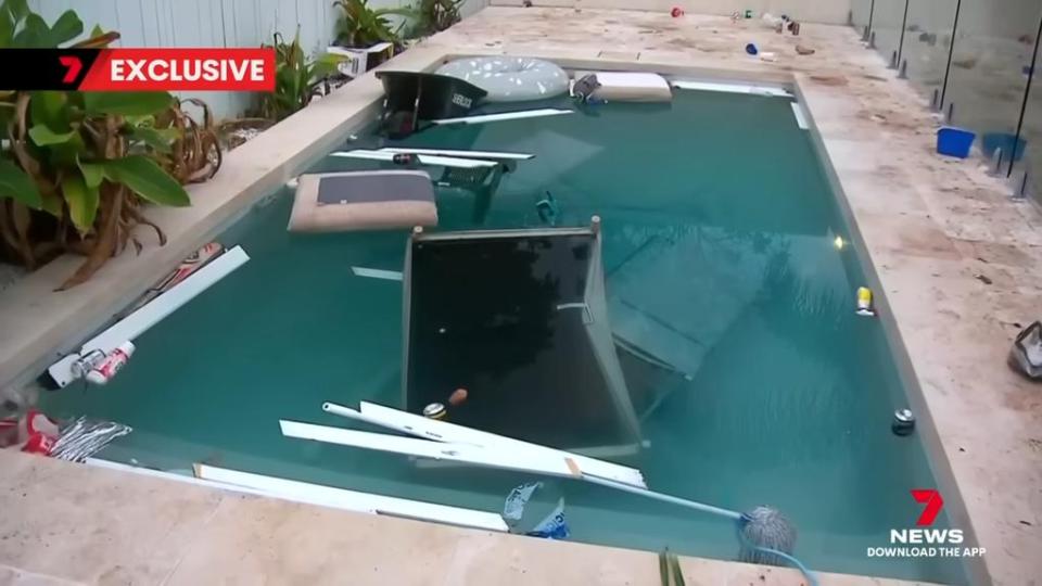Swimming pool with furniture and trash in it after a party.
