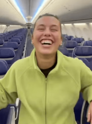 A laughing woman on a nearly empty airplane.