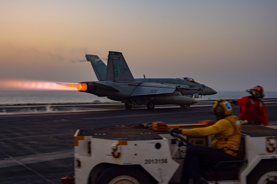 F/A-18E Super Hornet launching from aircraft carrier at sunset.