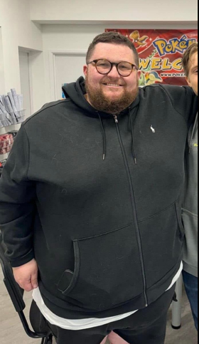 A large man wearing glasses and a black zip-up hoodie.