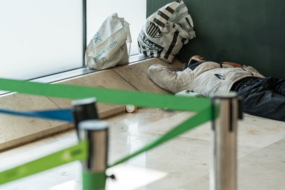 Person sleeping on the floor of an airport terminal.