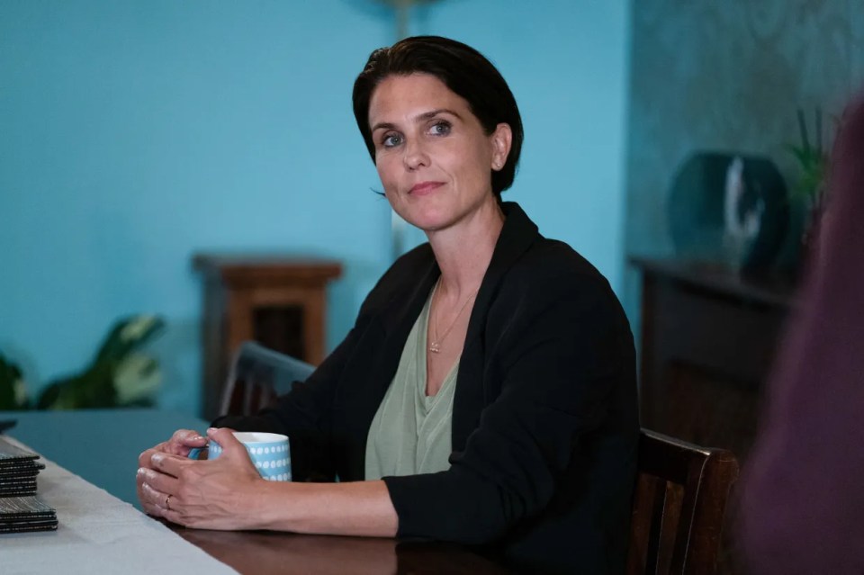 Woman sitting at a table, holding a mug.