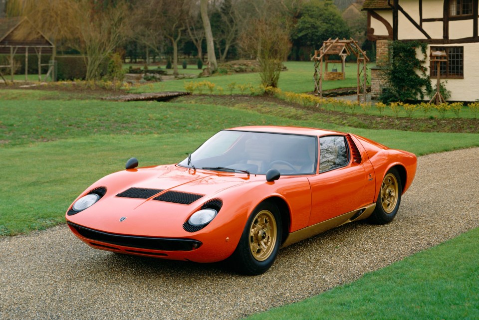 Orange Lamborghini Miura P400S parked on a gravel driveway.