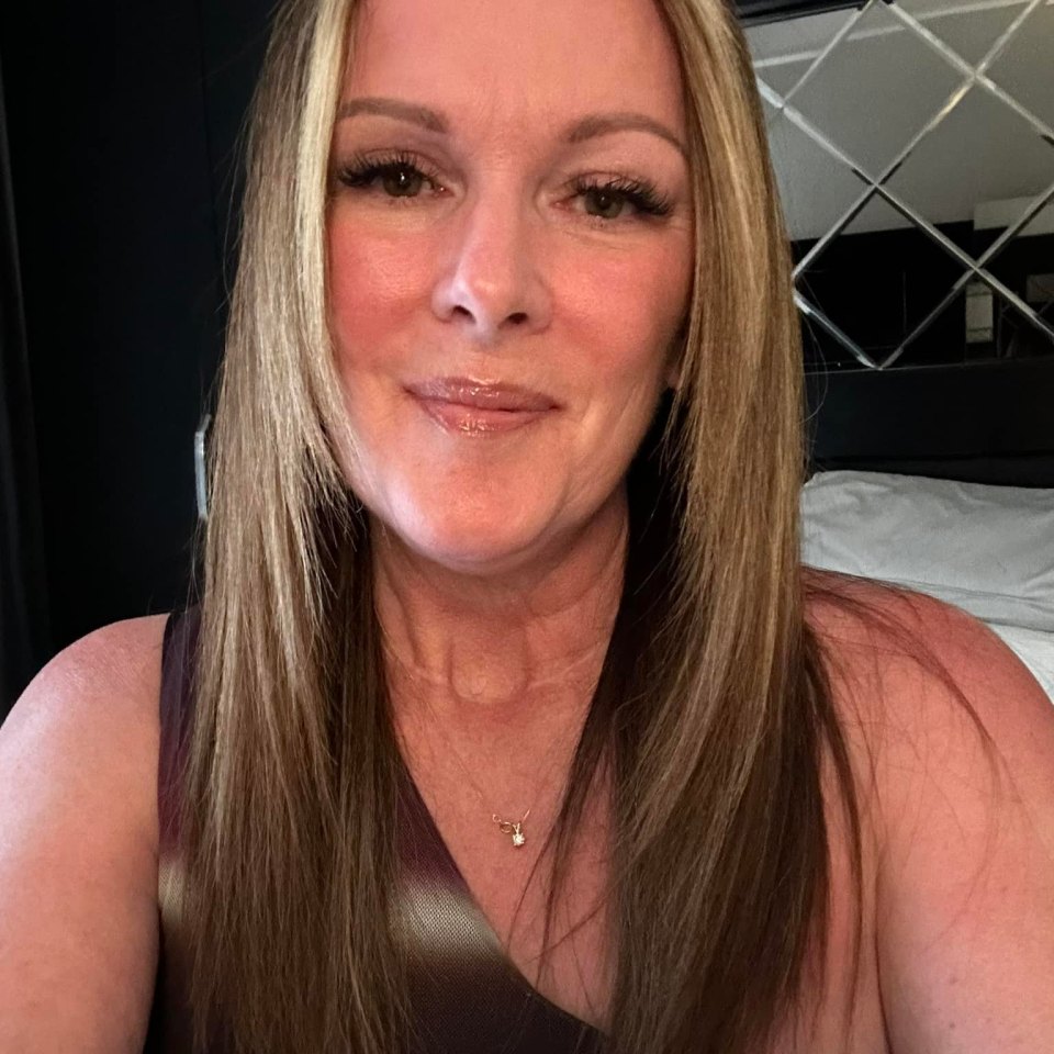 Woman with long brown hair wearing a sleeveless top.