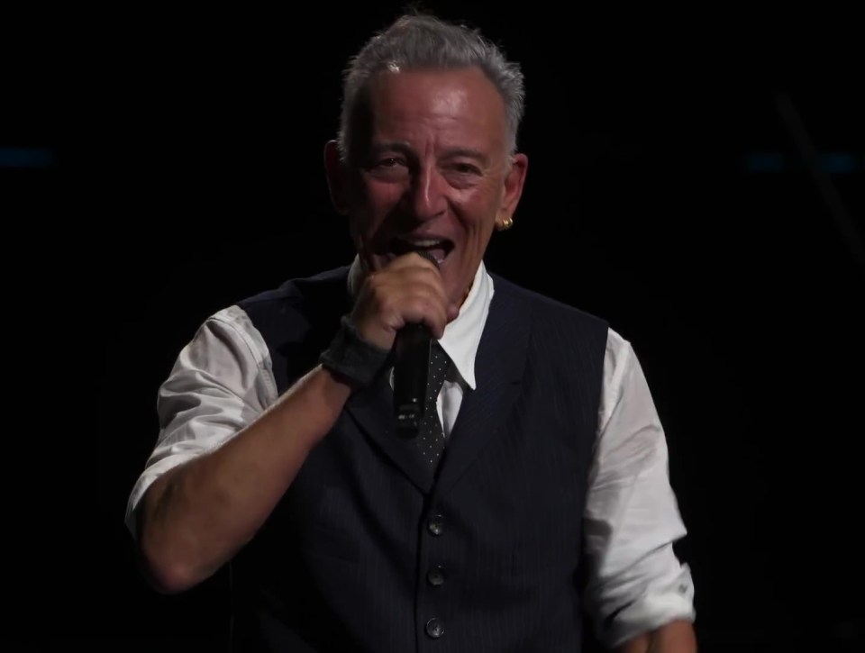 Bruce Springsteen speaking into a microphone at a concert.
