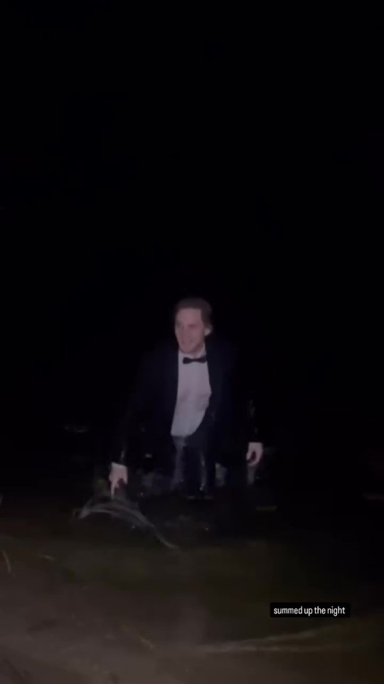 Man in tuxedo wading in dark water.