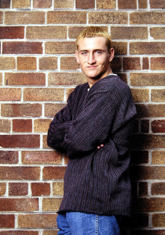 Photo of Will Mellor leaning against a brick wall.