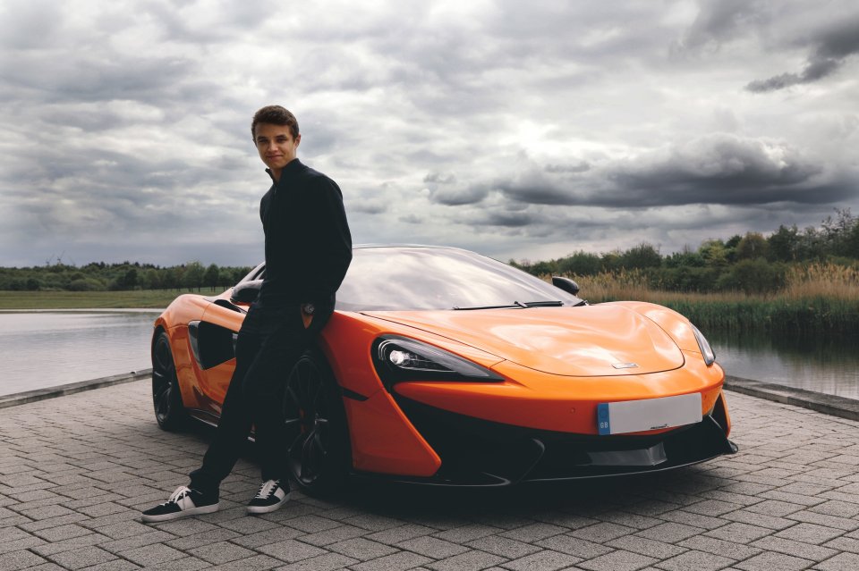 Lando Norris leaning against his orange McLaren.