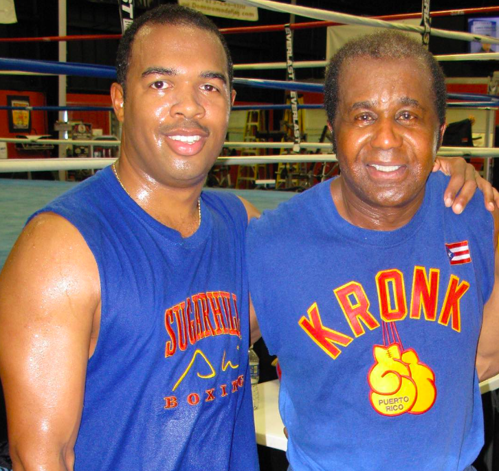 Two men in blue shirts at a boxing gym.