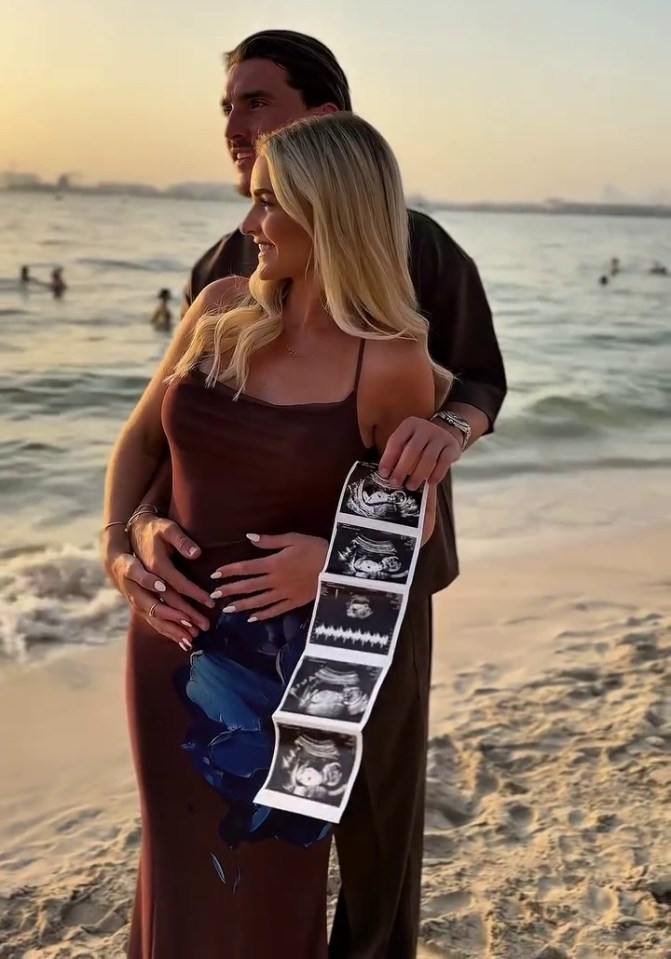 Pregnant woman and man on beach holding ultrasound images.