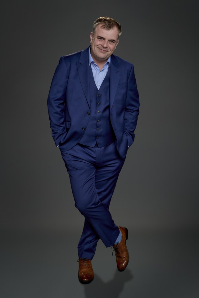 Portrait of Simon Gregson in a blue suit.