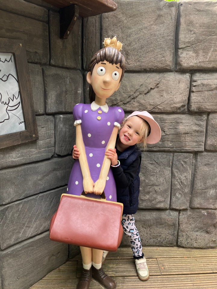 Young girl hugging a large statue of a girl at Warwick Castle.