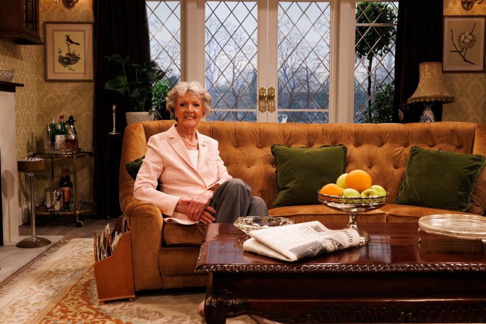 Dame Penelope Keith on a brown couch in a set from *The Good Life*.
