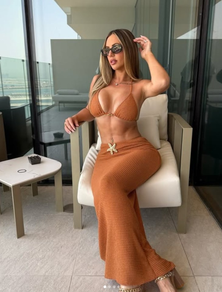 Woman in a rust-colored bikini and matching maxi skirt sitting on a chair on a balcony.
