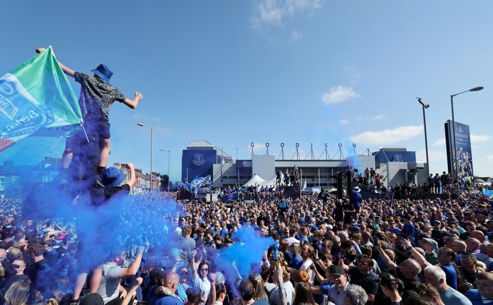 Everton fans celebrating outside Goodison Park with blue flares.
