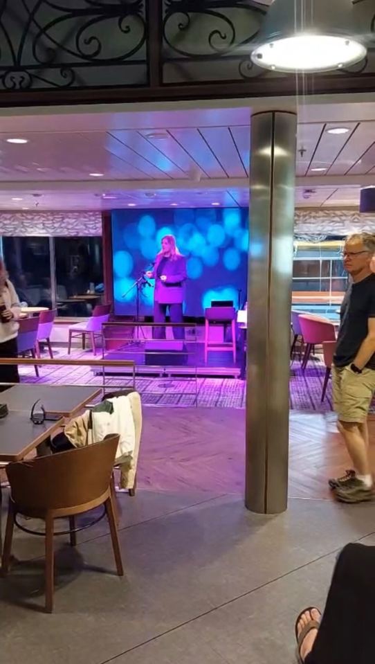 Woman singing on stage in a ferry lounge.
