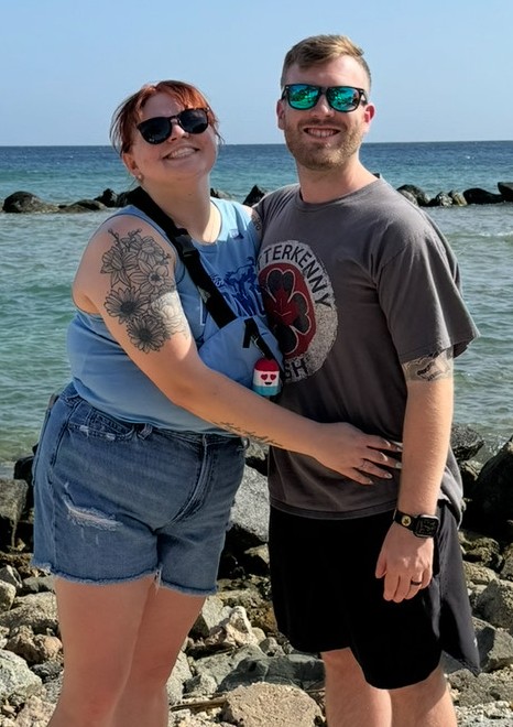 Couple posing for a photo by the ocean.