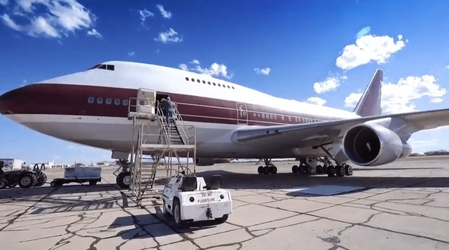 A large passenger plane on the tarmac with ground crew.