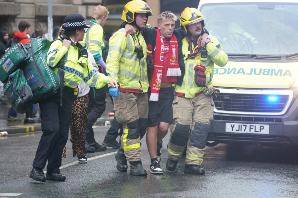 Two firefighters assisting an injured person, a police officer nearby.