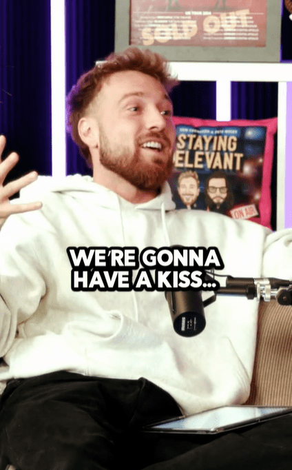 Man in a white hoodie says, "We're gonna have a kiss..." during a podcast recording.
