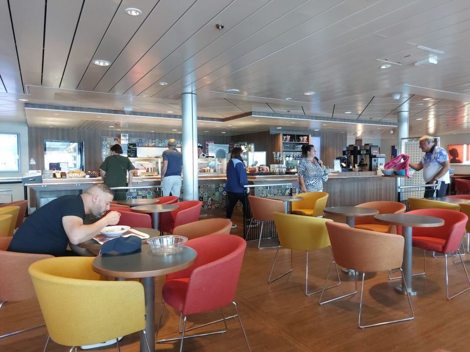 Passengers eating and waiting for food in a ship's cafeteria.