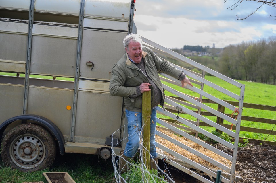 Jeremy Clarkson laughing while stuck near a livestock trailer on Clarkson's Farm.