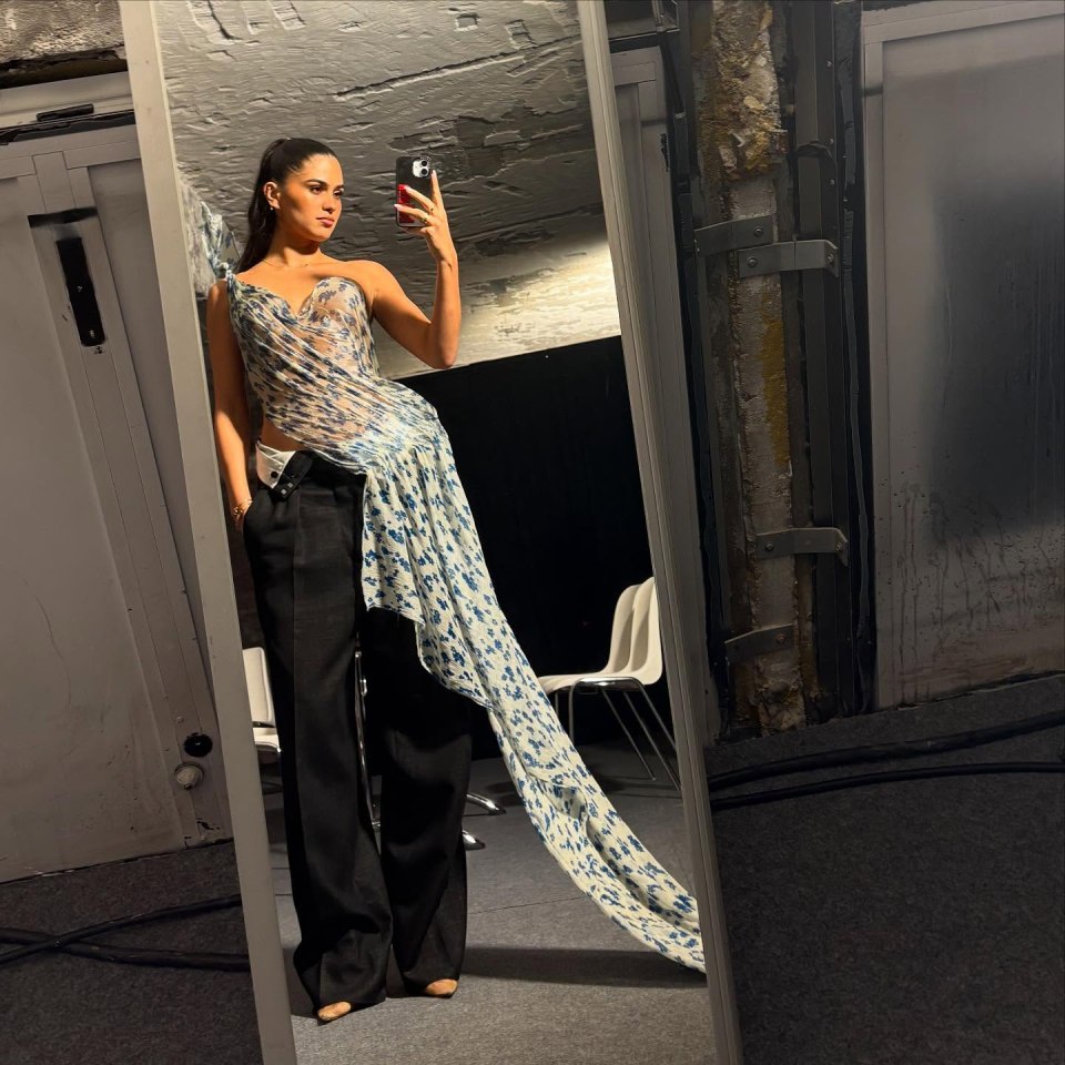 Katie Turnbull taking a selfie in a patterned top and black pants.