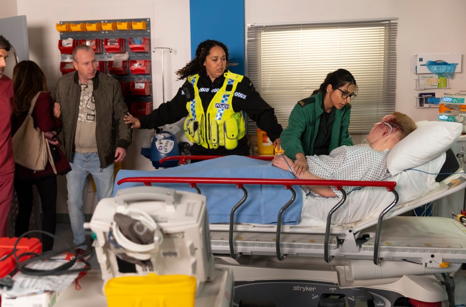 A bloodied man lies on a hospital gurney surrounded by police and paramedics.