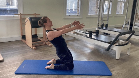 Woman performing a Pilates exercise on her knees.