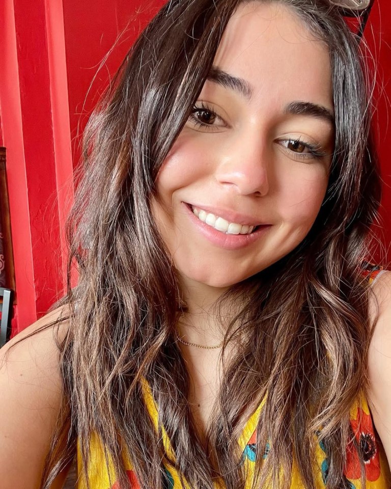Close-up portrait of a smiling woman with long brown hair.