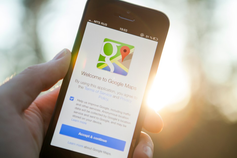 Hand holding iPhone displaying Google Maps welcome screen.