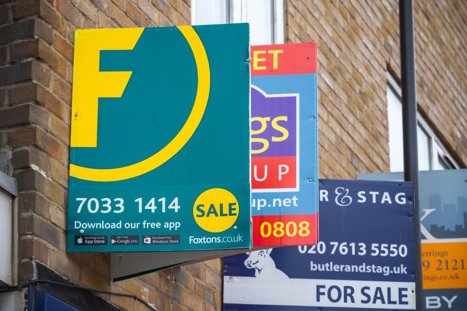 Estate agent signs displayed on a brick wall.