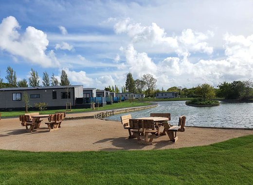 Picnic tables by a lake at Mill Rythe Holiday Park.