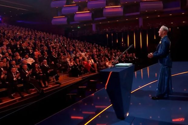 An image collage containing 1 images, Image 1 shows A person giving a speech to a large audience in a theater