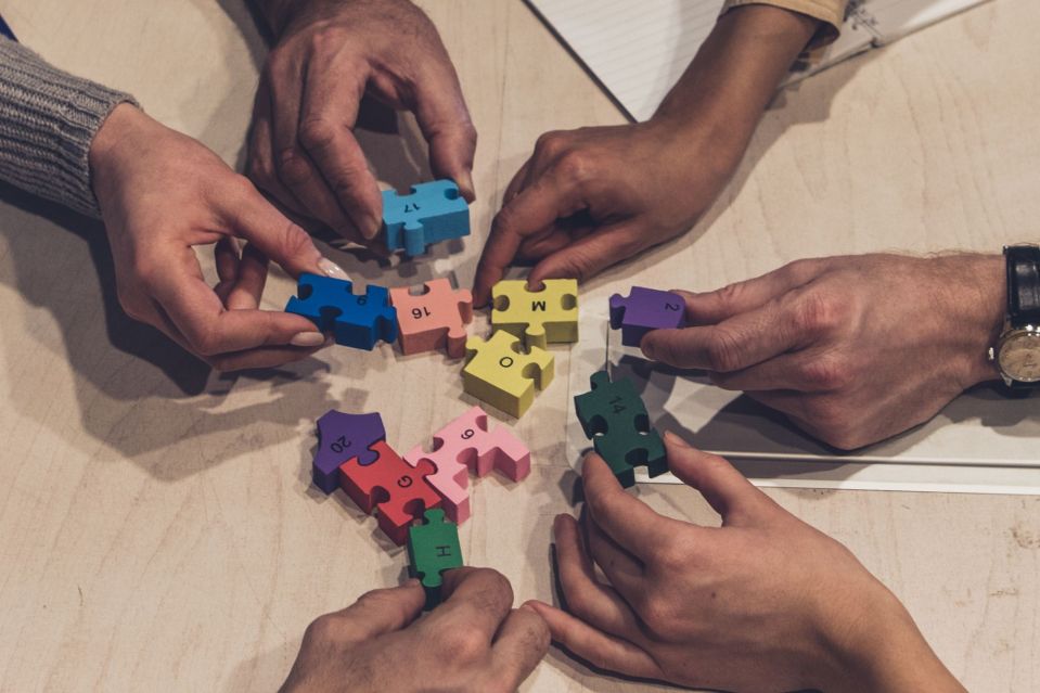 An image collage containing 1 images, Image 1 shows Group of businesspeople collaborating on a jigsaw puzzle