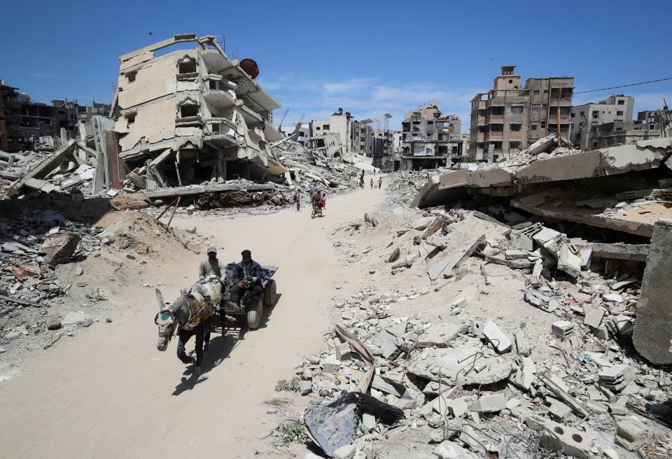 Two Palestinians ride a donkey cart past rubble in Gaza City.