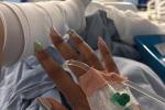 Person in hospital bed with IV drip.