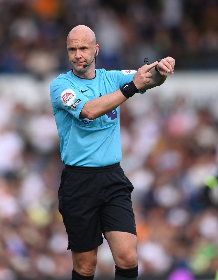 Referee Anthony Taylor checking his watch during a soccer match.