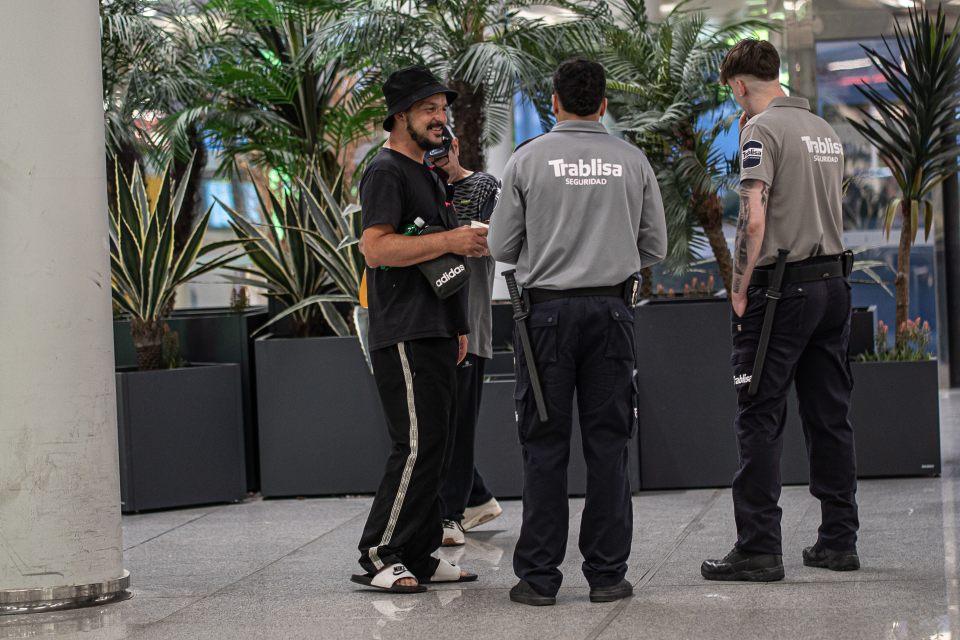 Homeless person at an airport speaking with security guards.