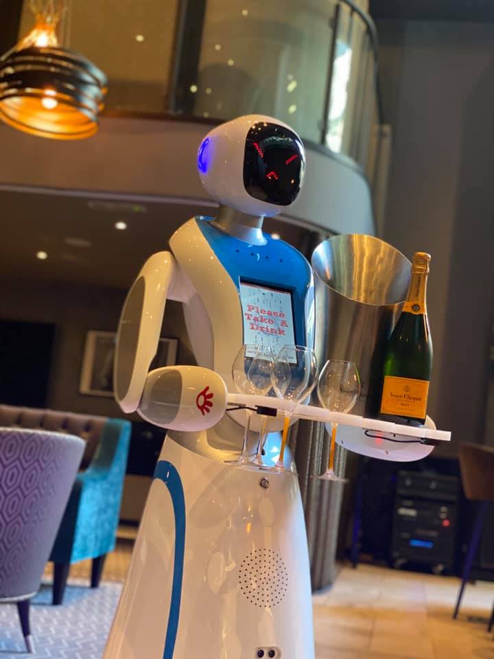 Robot waiter carrying champagne and glasses.